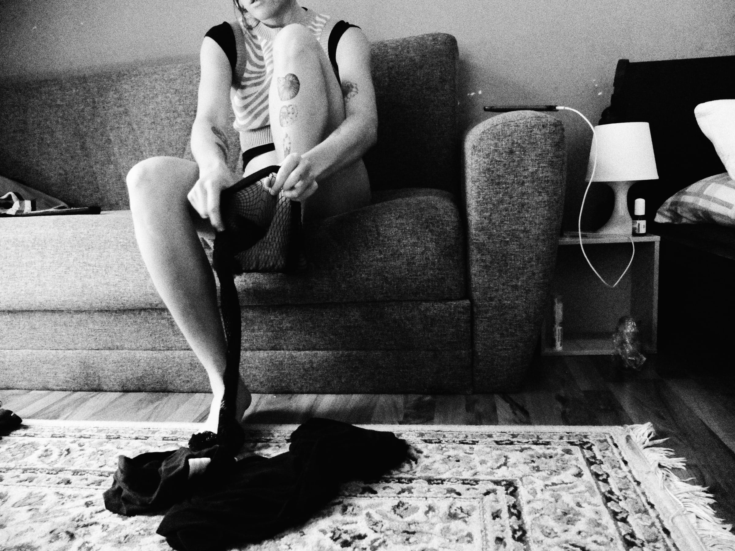Woman sitting on a sofa, getting dressed