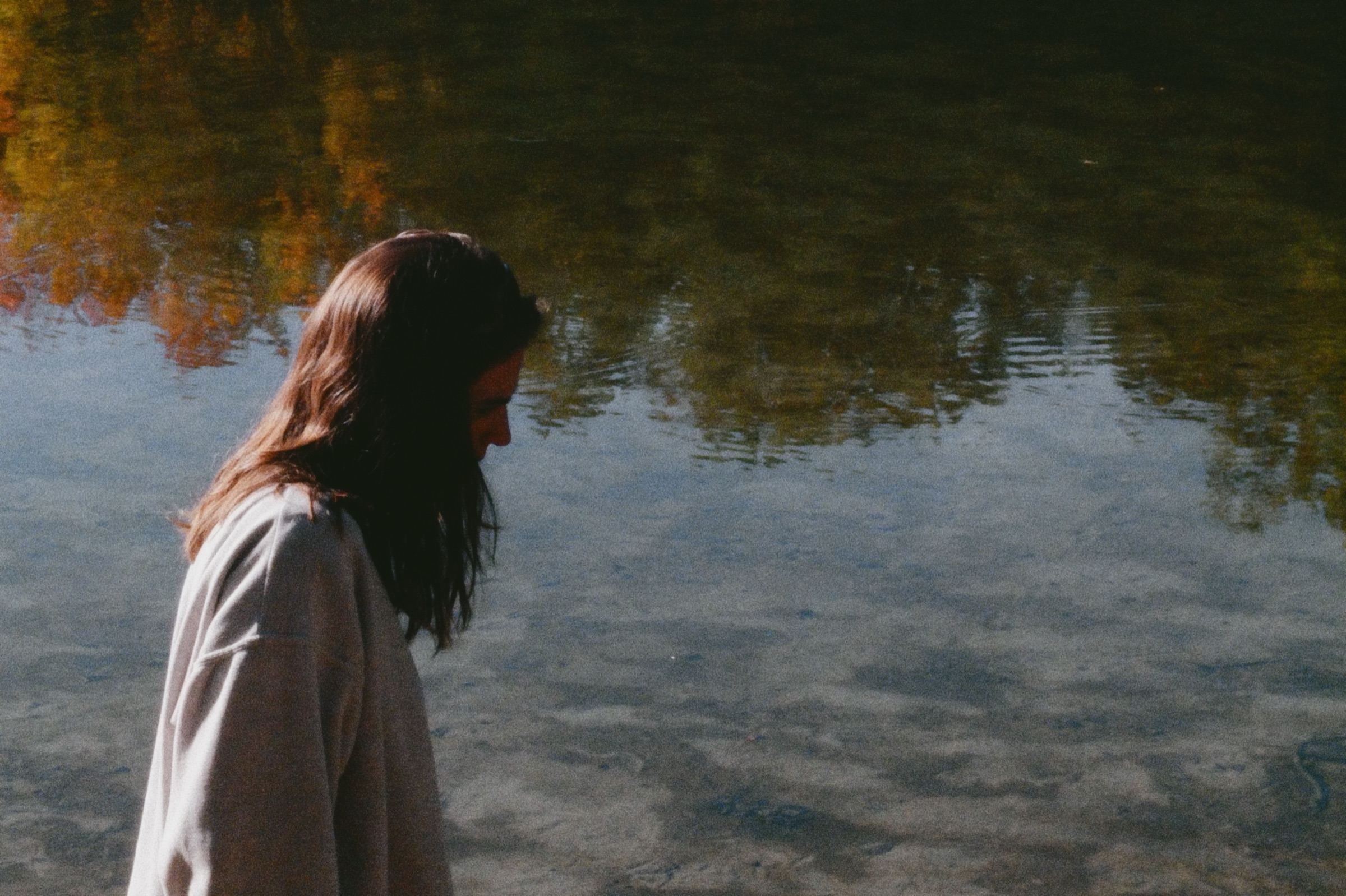 Woman looking down at trees reflected in the water