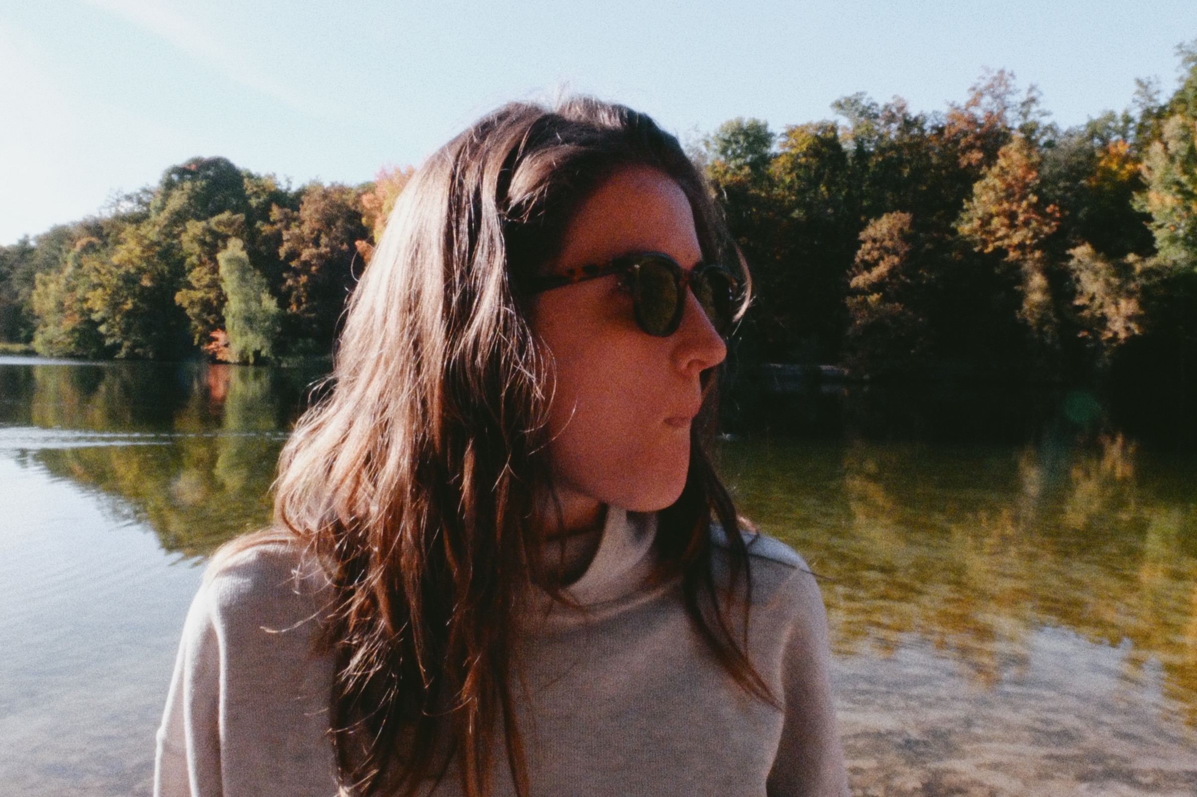 Woman in sunglasses by a lake in autumn light