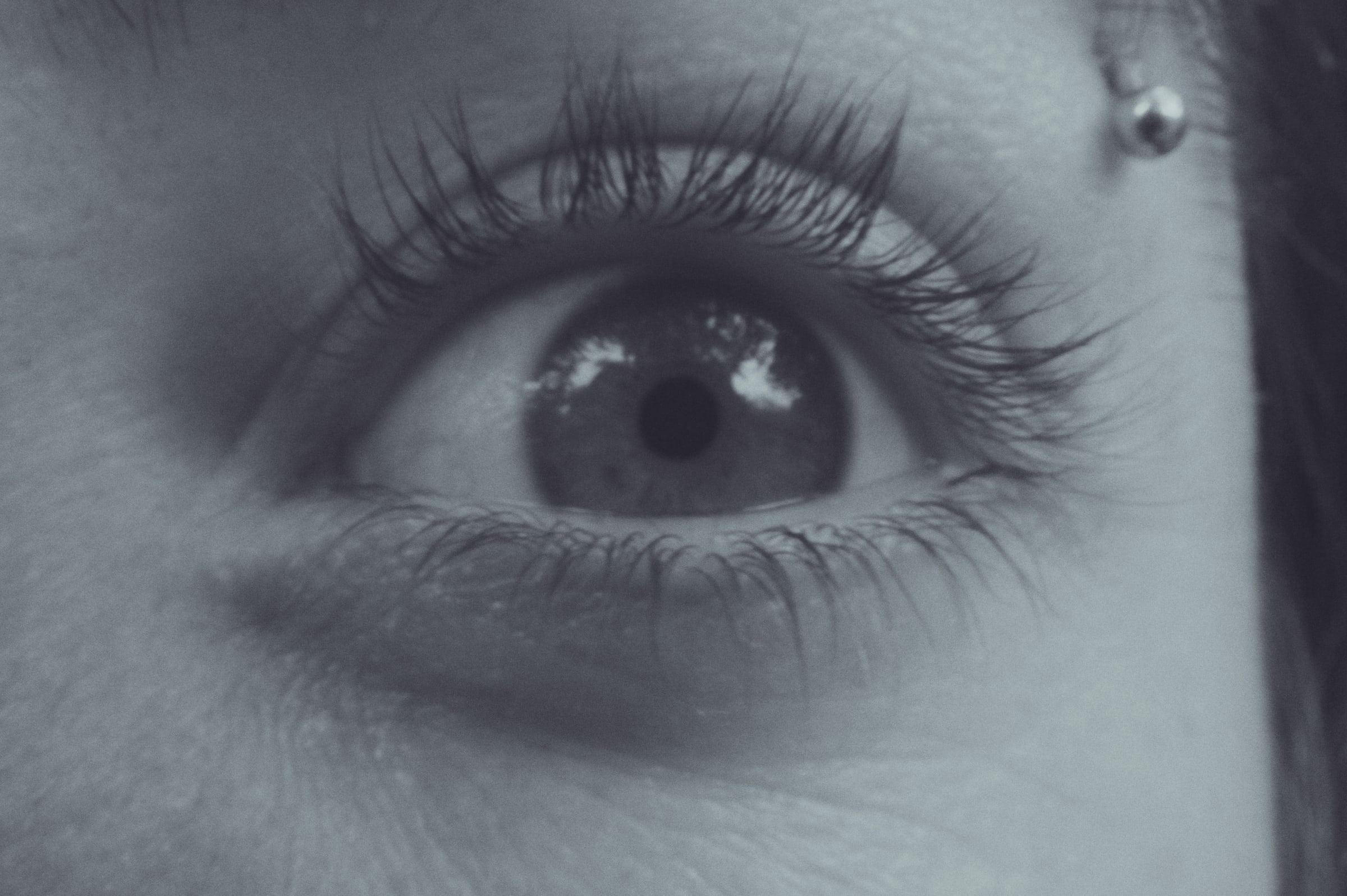 Close-up of an eye with long lashes and a piercing