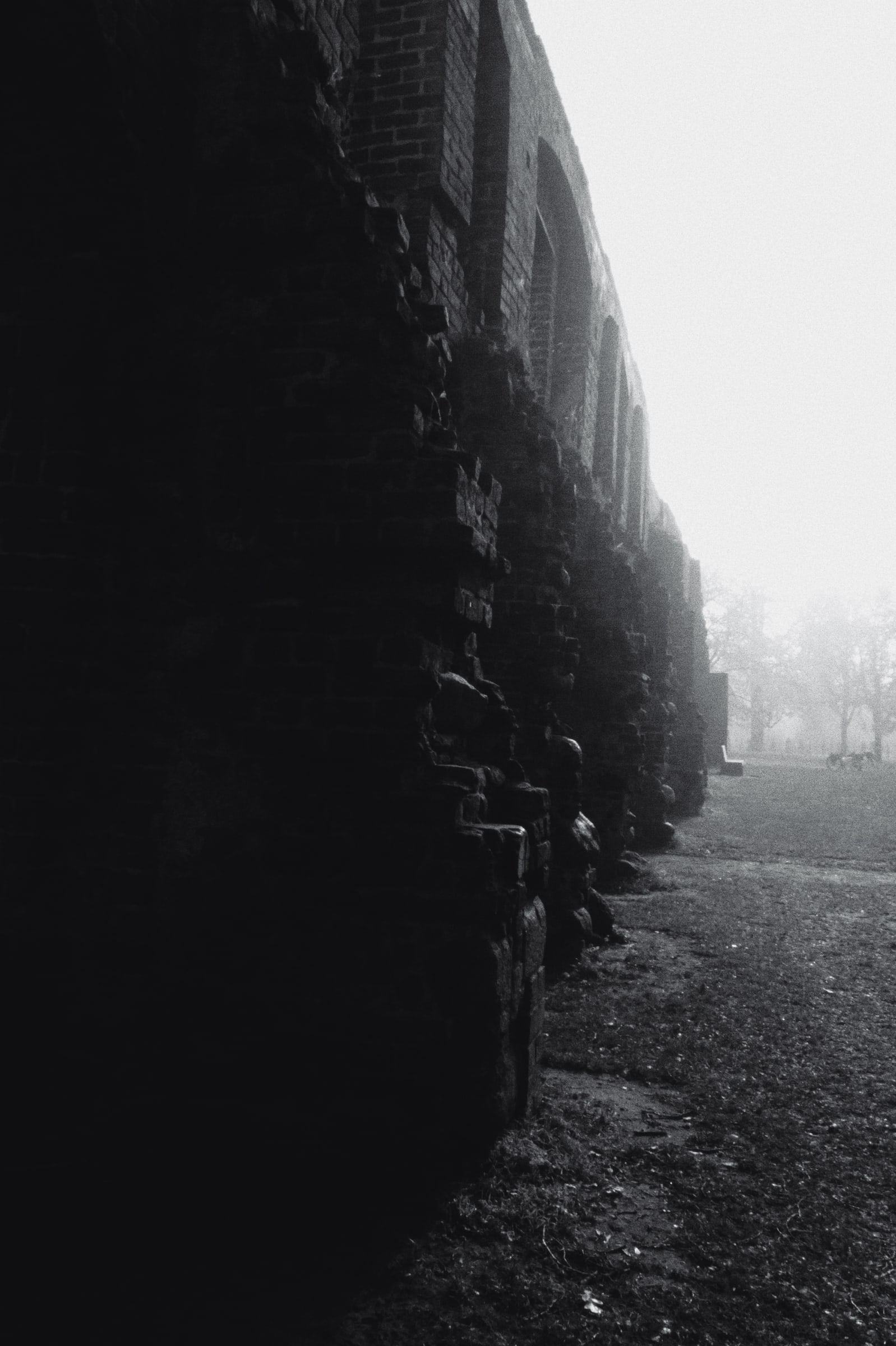 Ruined wall beside a path in fog