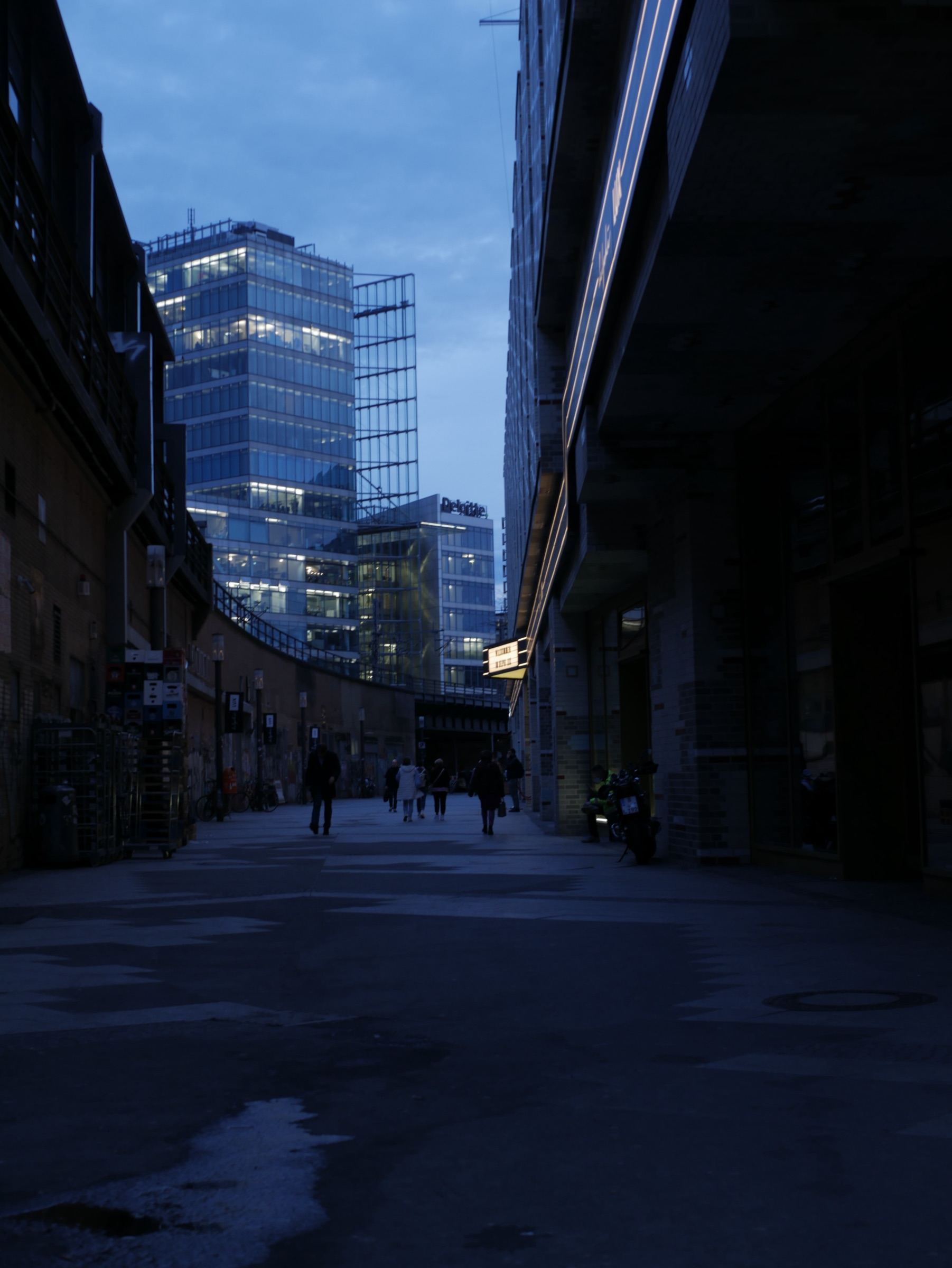 City street at dusk beneath lit glass towers