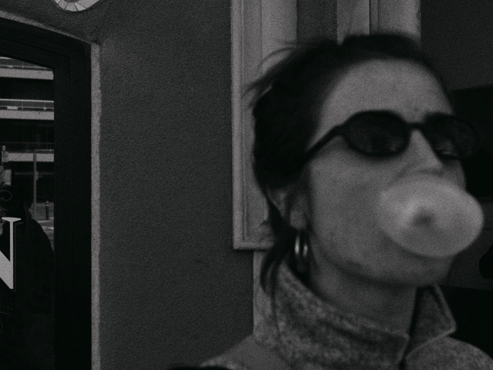 Woman in sunglasses blowing a bubblegum bubble