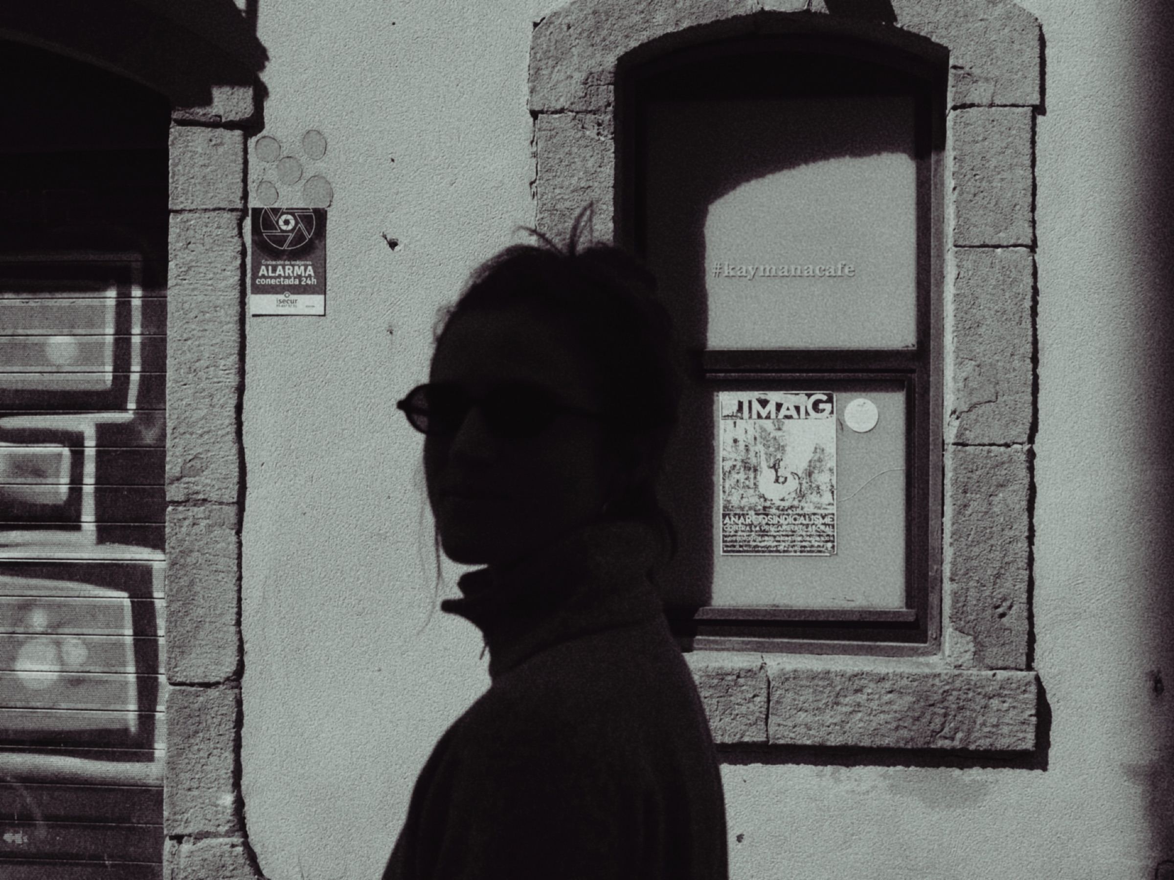Woman in sunglasses in silhouette beside a window