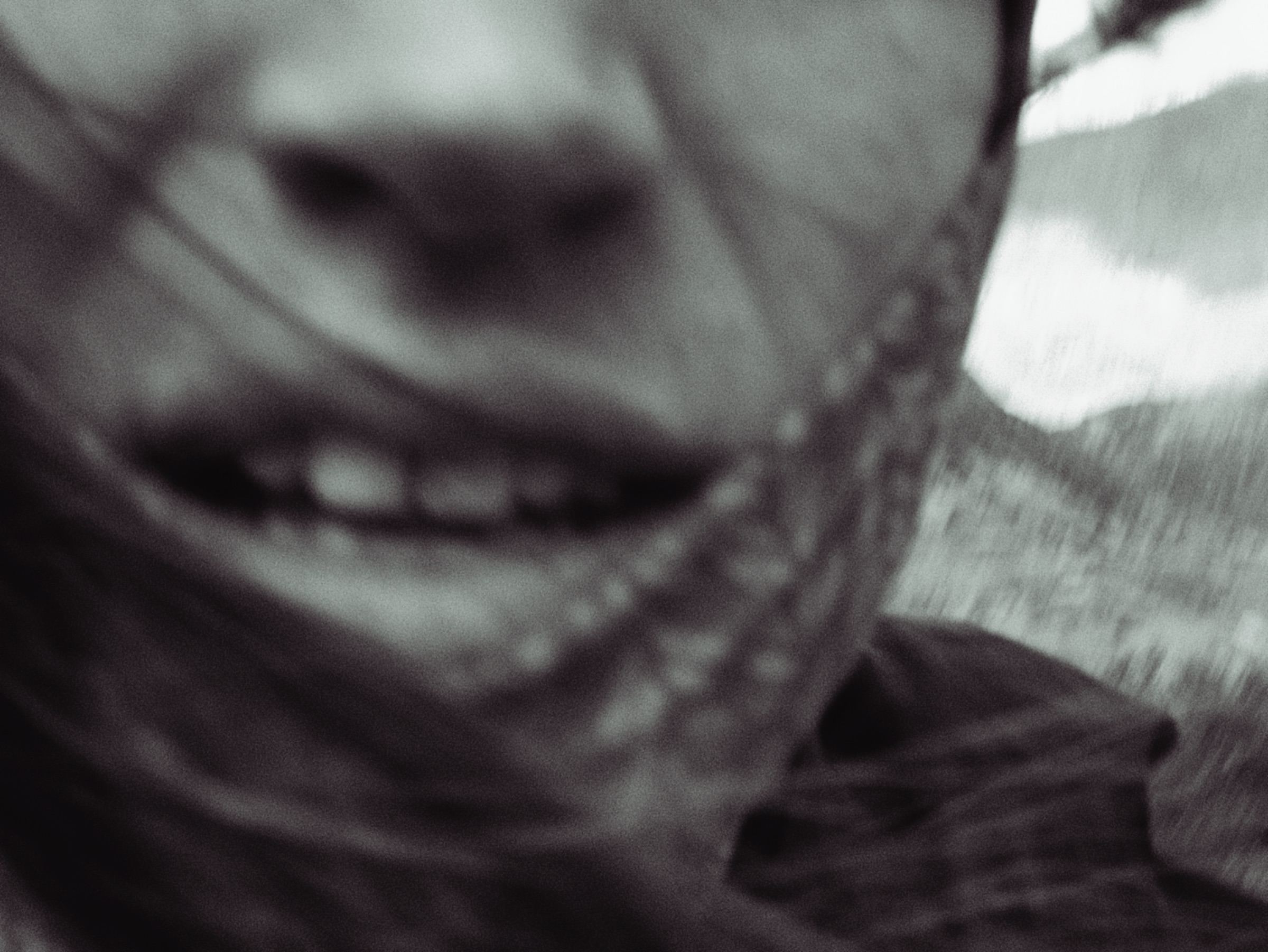 Close-up of a smiling mouth with hair blowing across it