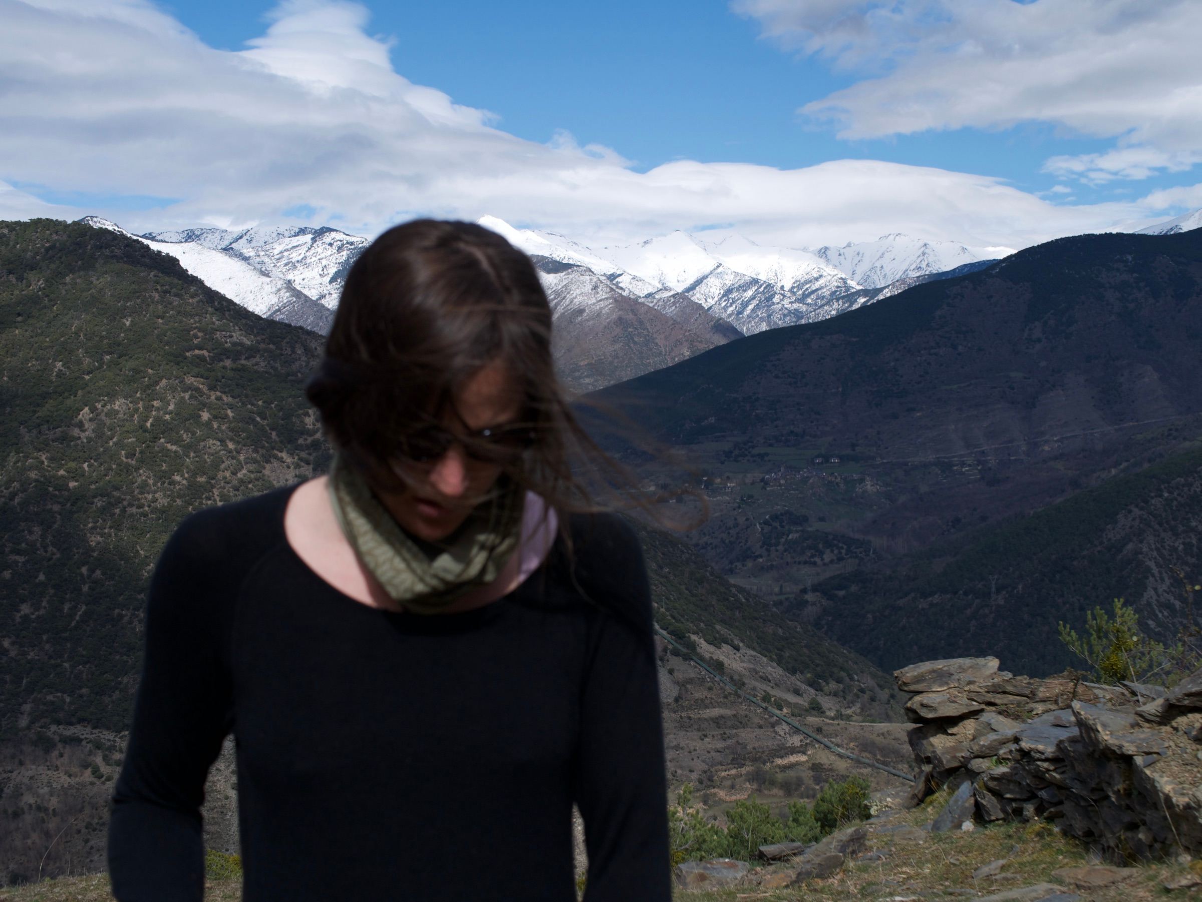 Woman with windswept hair in front of snow-capped mountains