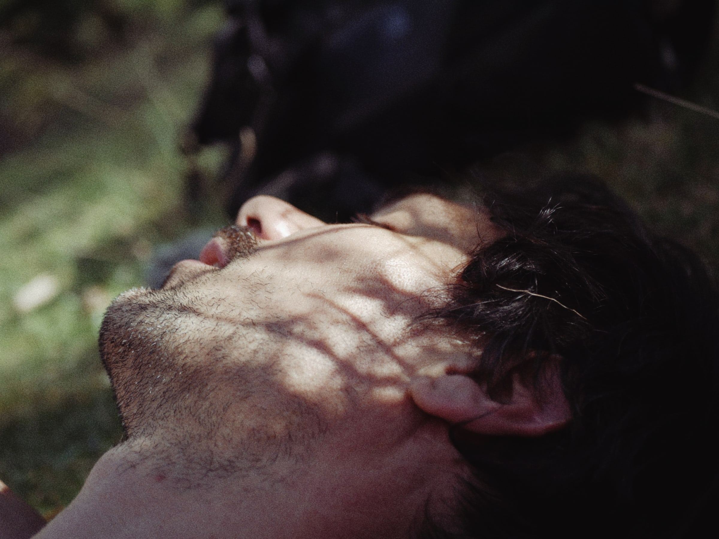 Man lying back, his face in dappled sunlight