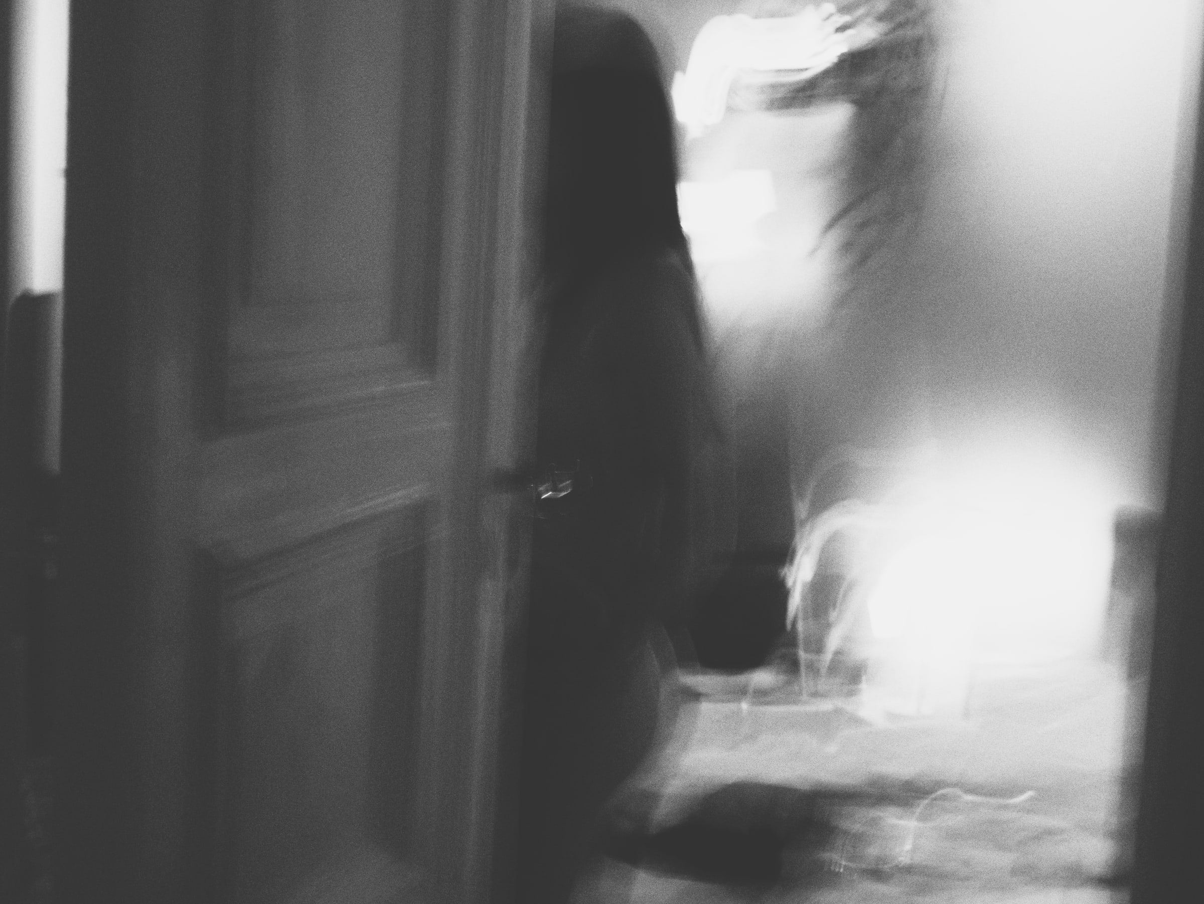 Blurred figure by a door, flooded with white light