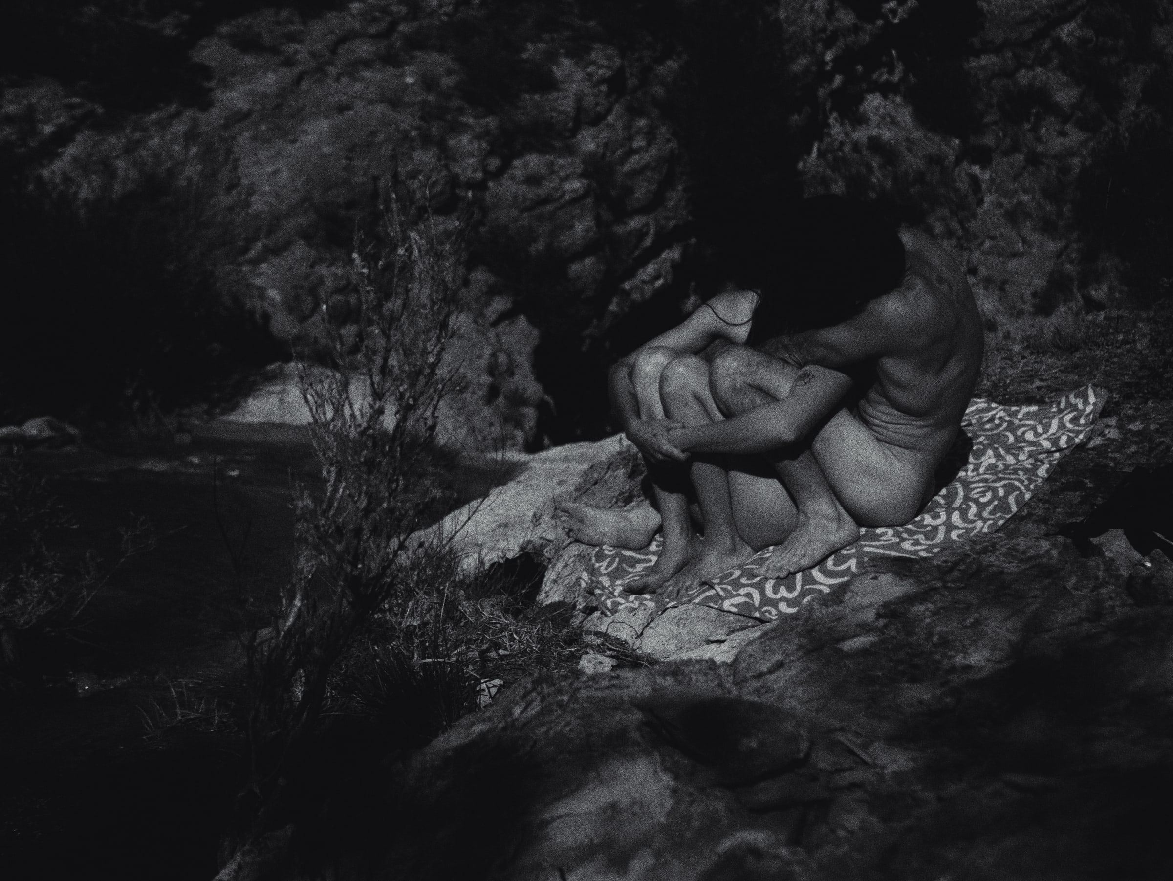 Person sitting on a patterned blanket among rocks