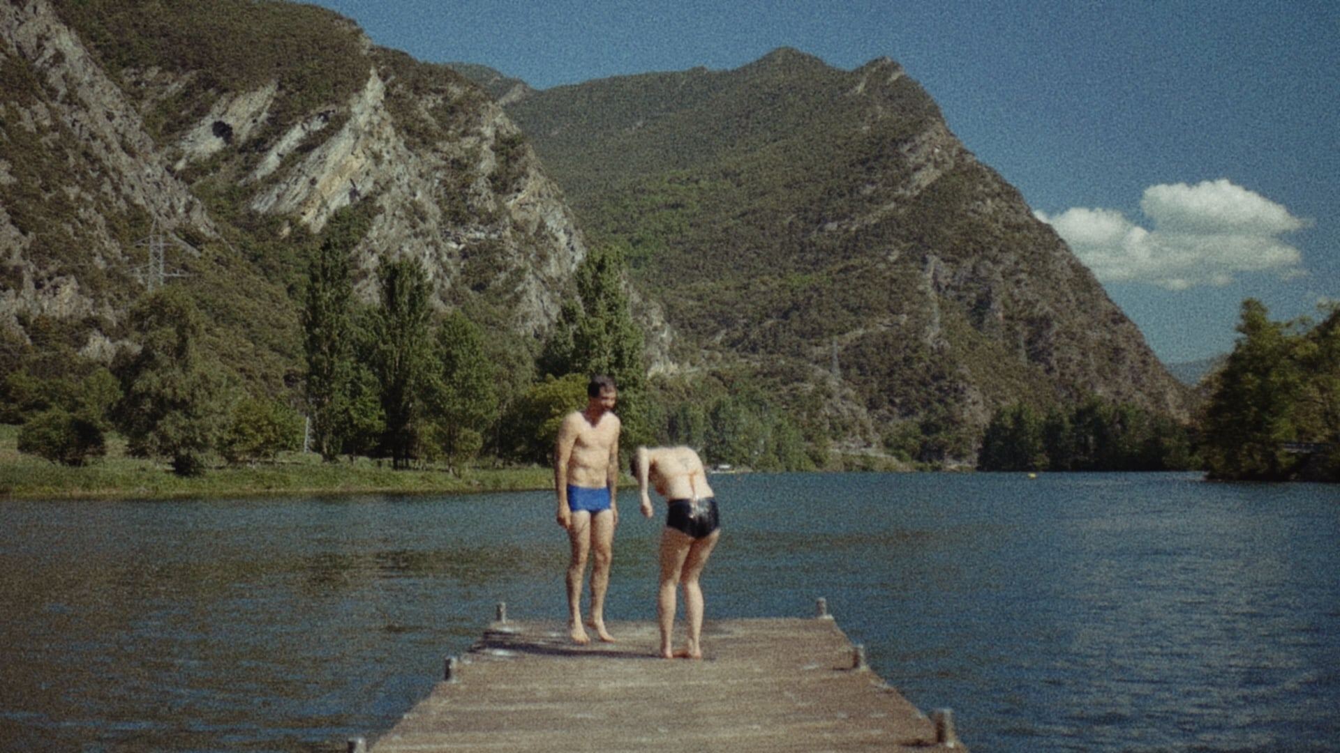 Two people on a jetty, one leaning toward the water