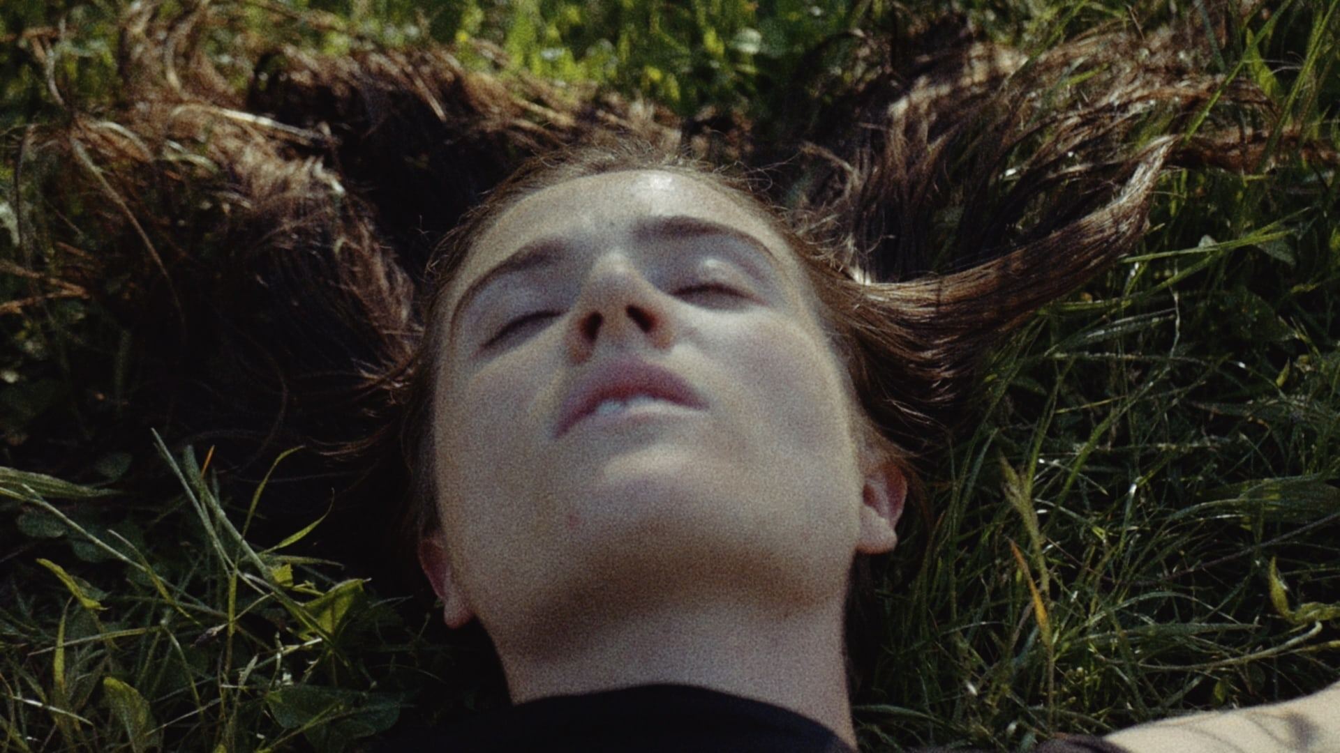 Woman lying in the grass with her eyes closed