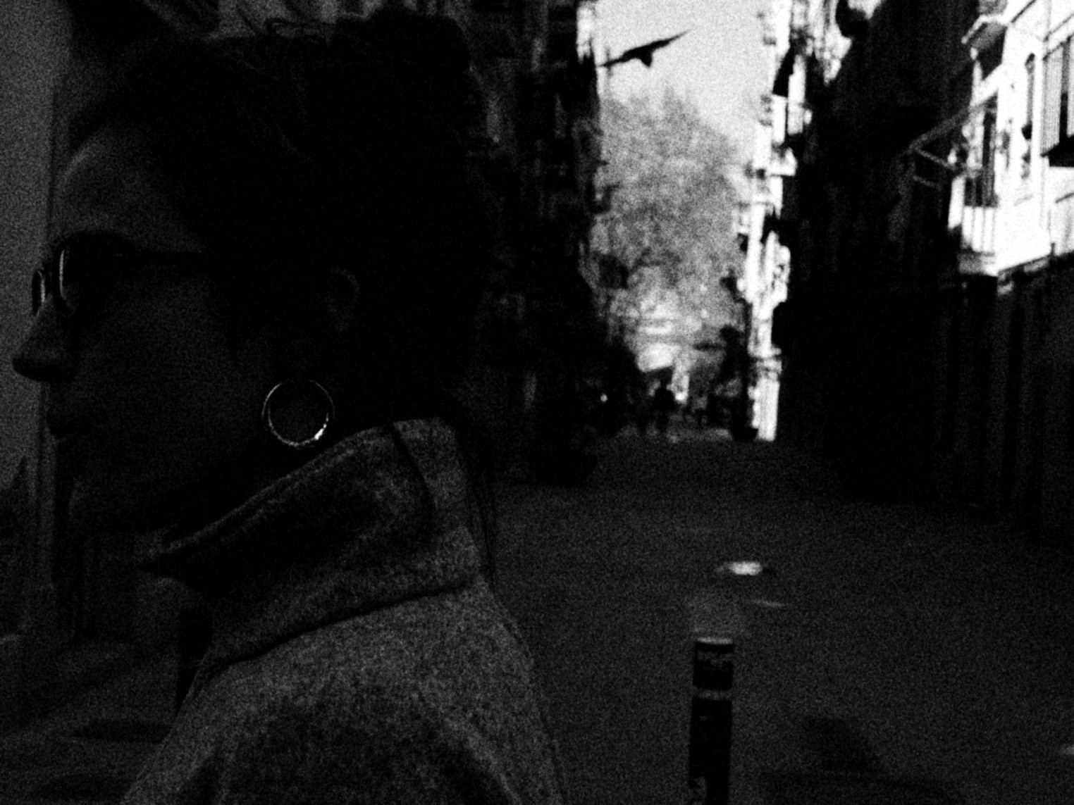 Mujer de perfil con anteojos en una calle angosta