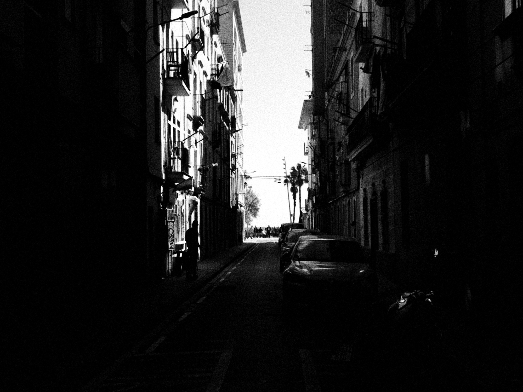 Calle angosta entre edificios altos, con la luz al fondo