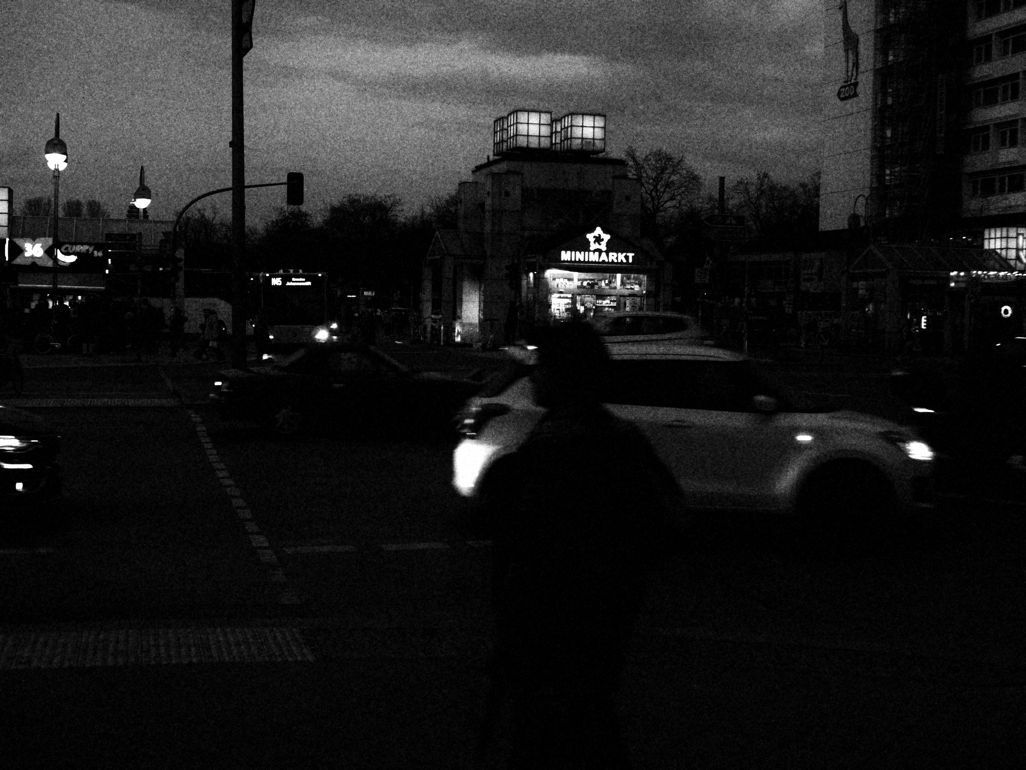 Figura cruzando la esquina de noche entre autos