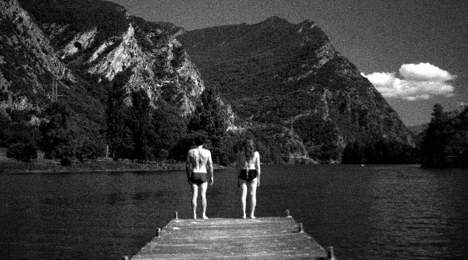 Dos personas paradas en un muelle frente a un lago y montañas, en los Pirineos