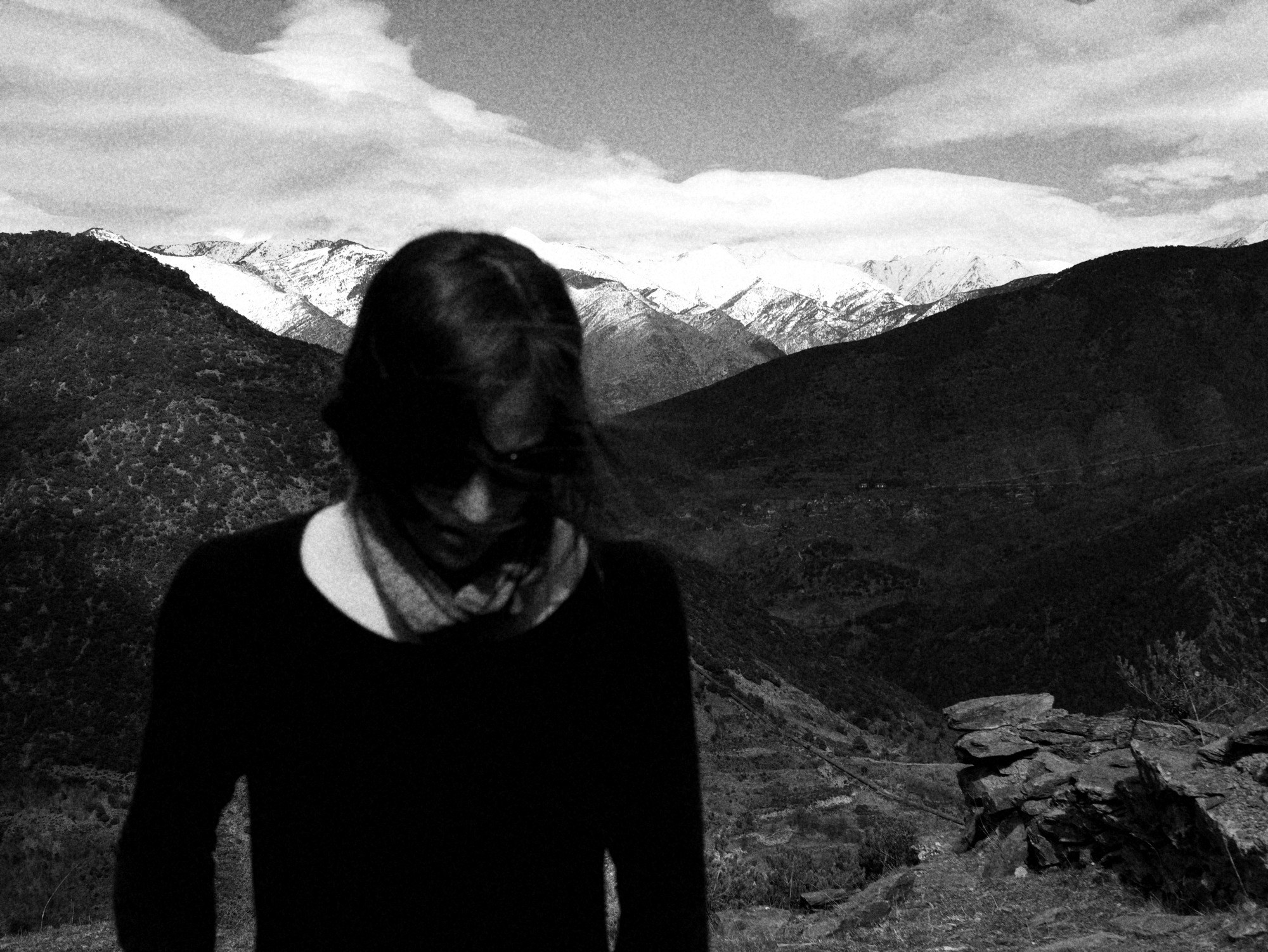Mujer con el pelo sobre la cara delante de montañas