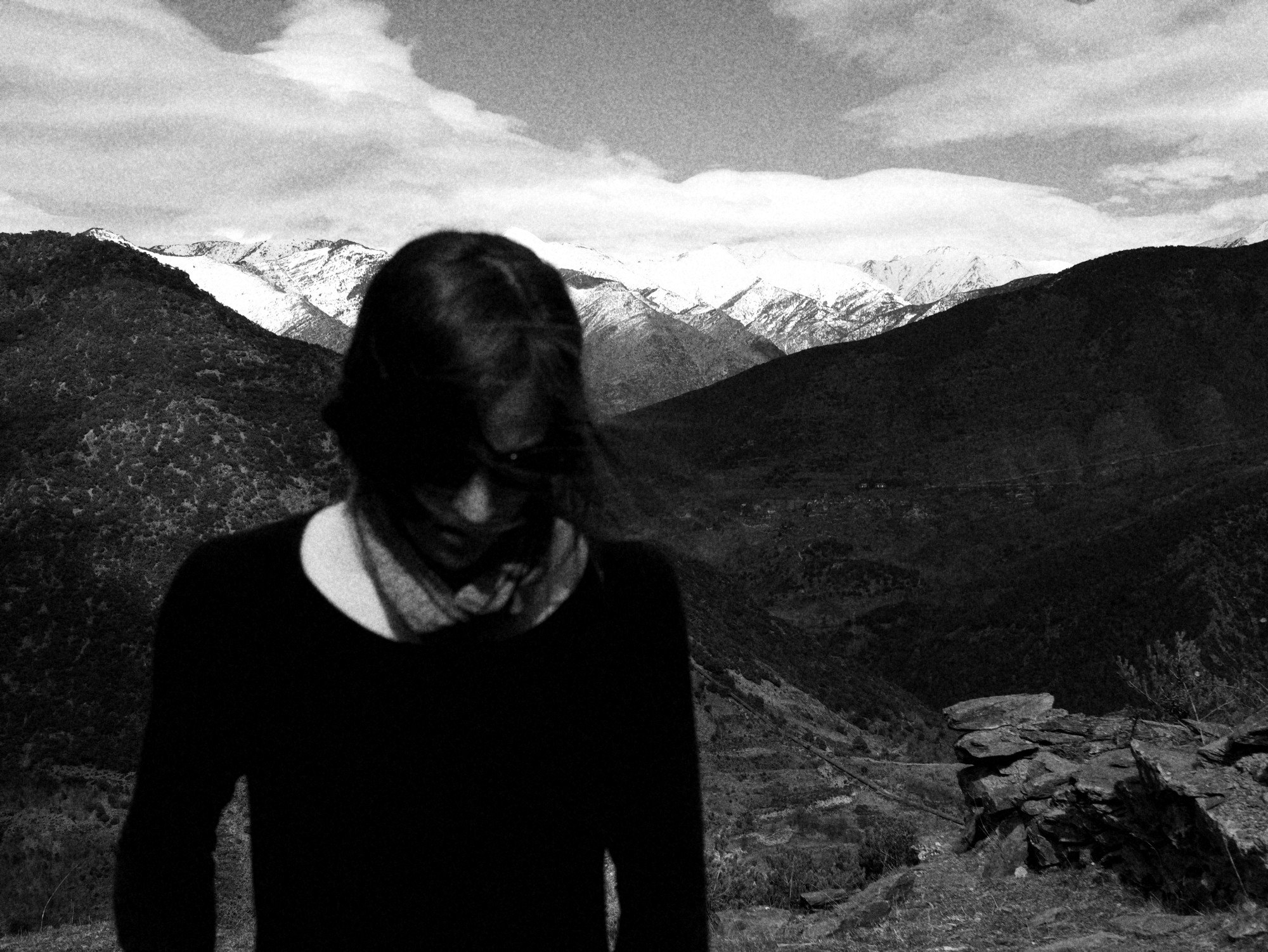 Mujer con el pelo sobre la cara delante de montañas nevadas en los Pirineos