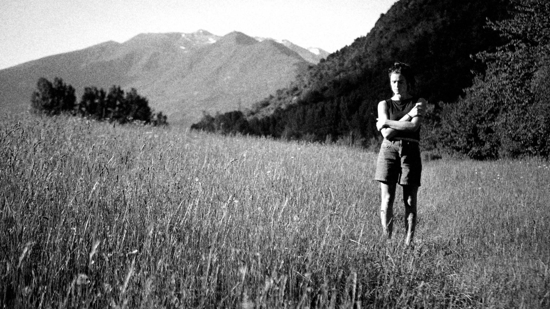 Persona parada en un prado debajo de montañas, en los Pirineos
